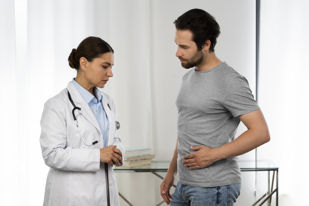 side view of a man talking to a female doctor while holding his stomach