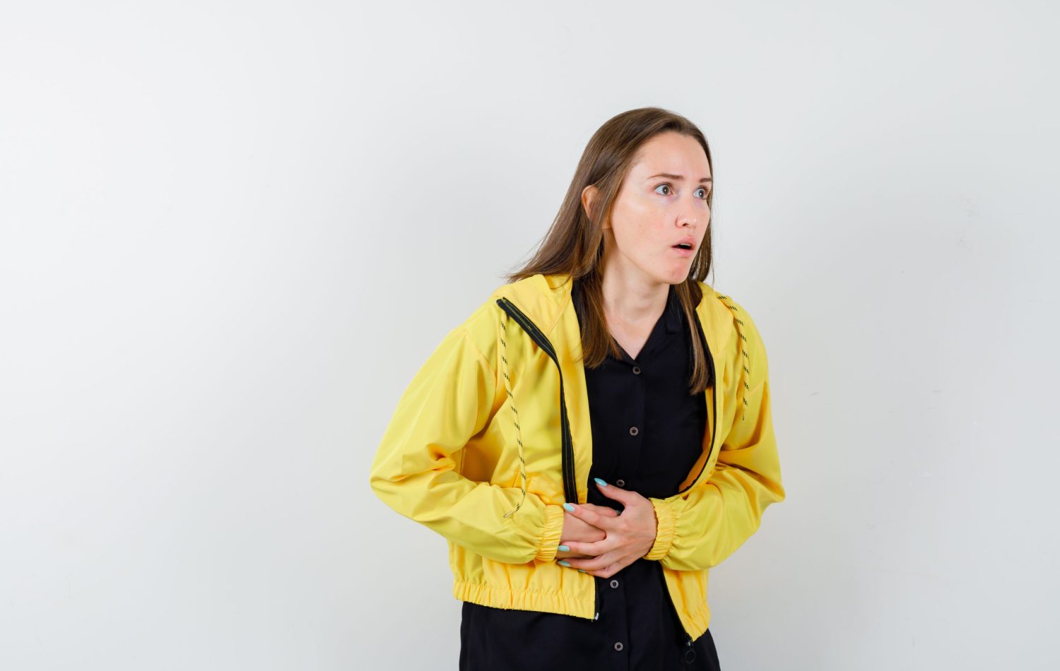young girl in black blouse, yellow jacket having bellyache and looking exhausted , front view.